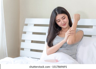 Young Beautiful Woman Rubbing Skin Lotion On Her Arm With Happily On Bed At Home,healthcare Skin Concept