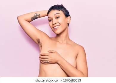 Young beautiful woman shirtless smiling happy. Standing with smile on face showing hairy armpit over isolated pink background
