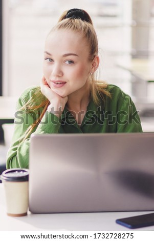 Young beautiful woman sits with a laptop, soft focus background