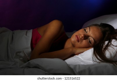 Young Beautiful Woman Sleeping In Bed In Dark Bedroom