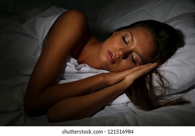 Young Beautiful Woman Sleeping In Bed In Dark Bedroom