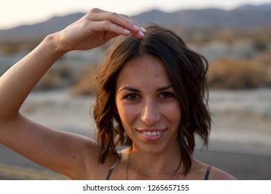 Young Beautiful Woman Smiles Towards Camera Close Up As She Is Being Goofy Placing Hand On Head - Young Adventure Fun