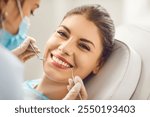 Young beautiful woman smiling at a dentist appointment, face close-up. The doctor holds dental instruments near the girls face. Concept of beautiful teeth and smile, tooth whitening