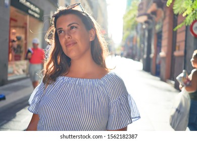 Junge schöne Frau lächelt glücklich spazieren auf den Straßen der Stadt an einem sonnigen Sommertag