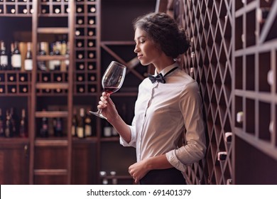 Young Beautiful Woman Sommelier Tasting Red Wine In Wine Cellar