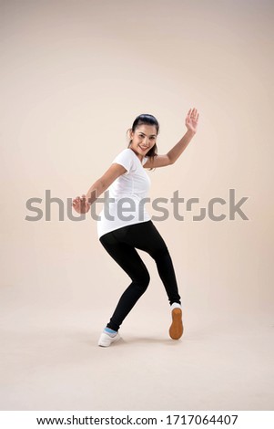 Young beautiful woman standing feet aparts,raise handsup in the air,little twisted,dance workout for exercise,with happy feeling