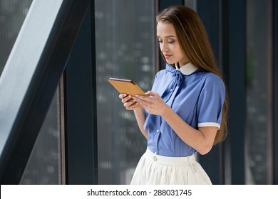 Young Beautiful Woman Standing With IPad And Reading.