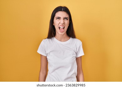 Young beautiful woman standing over yellow background angry and mad screaming frustrated and furious, shouting with anger. rage and aggressive concept.  - Shutterstock ID 2363829985