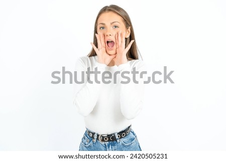 Young beautiful woman standing over white studio background shouting excited to front.