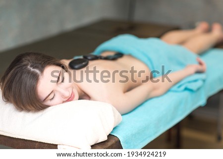 Young beautiful woman and stone massage in beauty spa