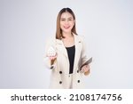 Young beautiful woman in suit holding small model house over white background studio