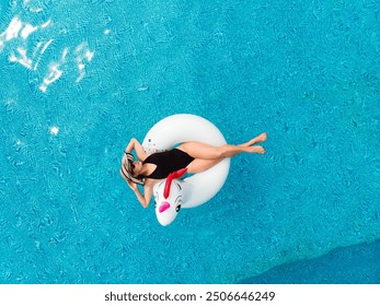 Young beautiful woman in swimsuit on inflatable unicorn pool float in pool in the hotel. Summer holidays - Powered by Shutterstock