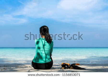 Young beautiful woman  in swimsuit sitting on white sand beach 