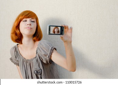 Young beautiful woman taking picture of herself, selfshot or selfy on mobile touch phone portrait