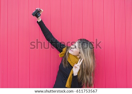 young beautiful woman taking a selfie with a vintage camera over red background. LIfestyle
