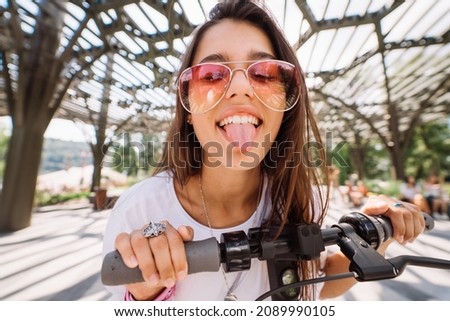 Young beautiful woman teasing and showing tongue at camera in park