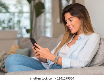 Young beautiful woman texting with phone on the sofa.