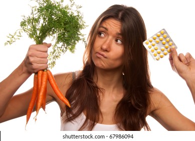 Young Beautiful Woman Thinks Deeply And Making Decision Between Organic Fresh Carrots And Medical Tablets To Make The Right Choice And Have No Doubts