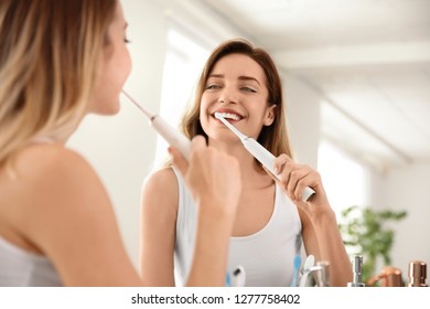 Young beautiful woman with toothbrush near mirror in bathroom. Personal hygiene