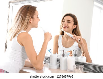 Young beautiful woman with toothbrush near mirror in bathroom. Personal hygiene