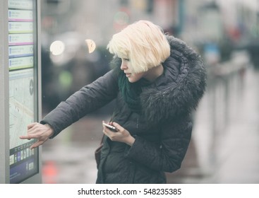 Young Beautiful Woman Tourist Using Modern Digital Display Board Information, Cute Female Watching Movement Of Buses On Electronic Bulletin Board In Urban City