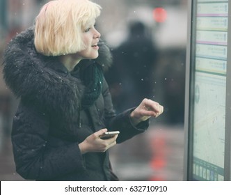 Young Beautiful Woman Tourist Using Modern Digital Display Board Information, Cute Female Watching Movement Of Buses On Electronic Bulletin Board In Urban City