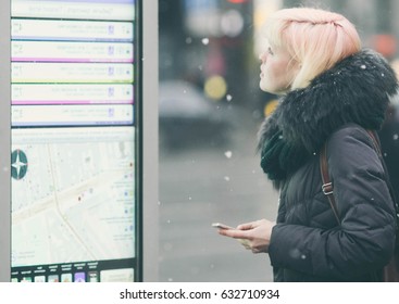 Young Beautiful Woman Tourist Using Modern Digital Display Board Information, Cute Female Watching Movement Of Buses On Electronic Bulletin Board In Urban City