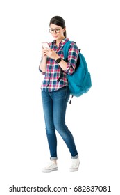 Young Beautiful Woman Traveler Carrying Personal Luggage Bag Standing On White Background And Using Mobile Cell Phone Searching Online Information Planning To Travel.