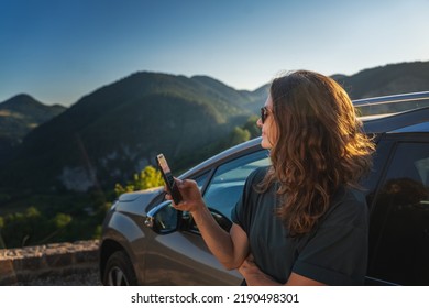 Young beautiful woman traveling by car in the mountains using smartphone at sunset, summer vacation and adventure - Powered by Shutterstock