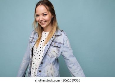 Young Beautiful Woman. Trendy Woman In Casual Summer Dress And Stylish Denim Jacket. Positive Female Shows Facial Emotions. Funny Model Isolated On Blue Background With Free Space