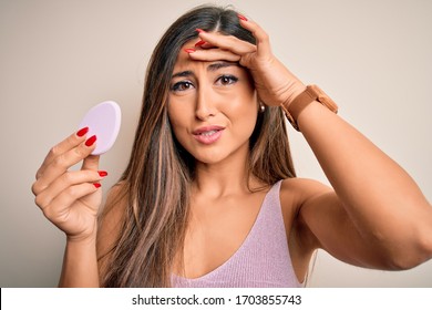 Young Beautiful Woman Using Beauty Sponge With Facial Makeup Over Pink Background Stressed With Hand On Head, Shocked With Shame And Surprise Face, Angry And Frustrated. Fear And Upset For Mistake.