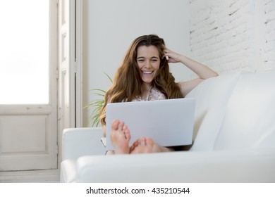 young beautiful woman using laptop computer laughing happy watching something funny or doing online internet shopping at home modern living room in cheerful and satisfied face expression