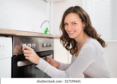 Young Beautiful Woman Using Microwave Oven In Kitchen