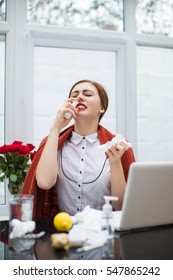 Young Beautiful Woman Using Nose Spray At Workplace