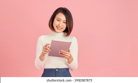 Young Beautiful Woman Using Smartphone Gadget Ipad.Lifestyle Concept. Isolated On Pink Background.