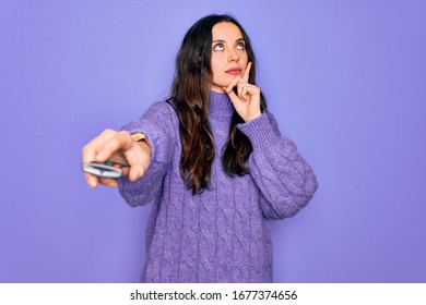 Young beautiful woman using television remote control over isolated purple background serious face thinking about question, very confused idea - Powered by Shutterstock