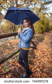 A Young Beautiful Woman Is Walking Along The Autumn Park With An Umberella In Her Hands. Autumn Portrait Of Young Happy Woman. Autumn. Rain.