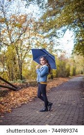 A Young Beautiful Woman Is Walking Along The Autumn Park With An Umberella In Her Hands. Autumn Portrait Of Young Happy Woman. Autumn. Rain.