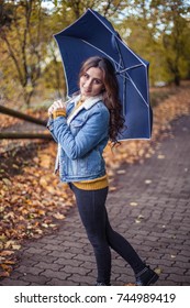 A Young Beautiful Woman Is Walking Along The Autumn Park With An Umberella In Her Hands. Autumn Portrait Of Young Happy Woman. Autumn. Rain.