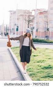 Young Beautiful Woman Walking In The City Holding Ukulele - Busker, City Living, Music Concept