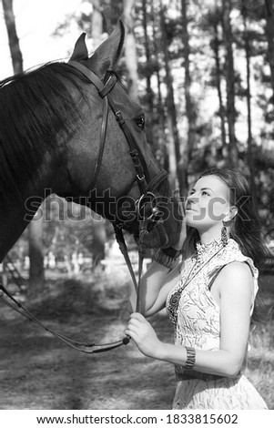 Young beautiful woman walking in the forest with her horse. Dressage. Black and white photography.