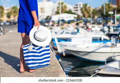 Young Beautiful Woman Walking With Hat And Bag On Dock Near The Boat