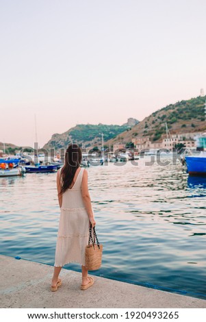 Young beautiful woman walking on dock near the boat 