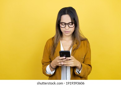 Young beautiful woman wearing a blazer over isolated yellow background texting with her phone