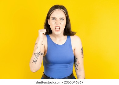 young beautiful woman wearing blue top angry and mad raising fist frustrated and furious while shouting with anger. Rage and aggressive concept. - Shutterstock ID 2365046867