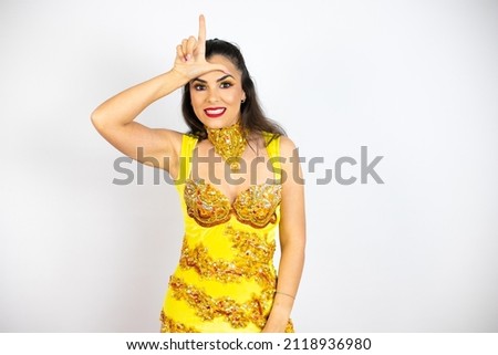Young beautiful woman wearing carnival costume over isolated white background making fun of people with fingers on forehead doing loser gesture mocking and insulting.