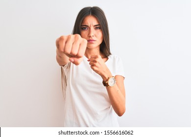 Young beautiful woman wearing casual t-shirt standing over isolated white background Punching fist to fight, aggressive and angry attack, threat and violence
