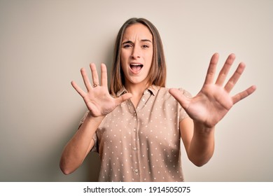 Young beautiful woman wearing casual shirt standing over isolated white background afraid and terrified with fear expression stop gesture with hands, shouting in shock. Panic concept. - Shutterstock ID 1914505075