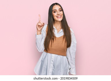 Young beautiful woman wearing casual white shirt pointing finger up with successful idea. exited and happy. number one. 