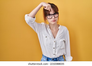 Young Beautiful Woman Wearing Casual Shirt Over Yellow Background Pointing Unhappy To Pimple On Forehead, Ugly Infection Of Blackhead. Acne And Skin Problem 